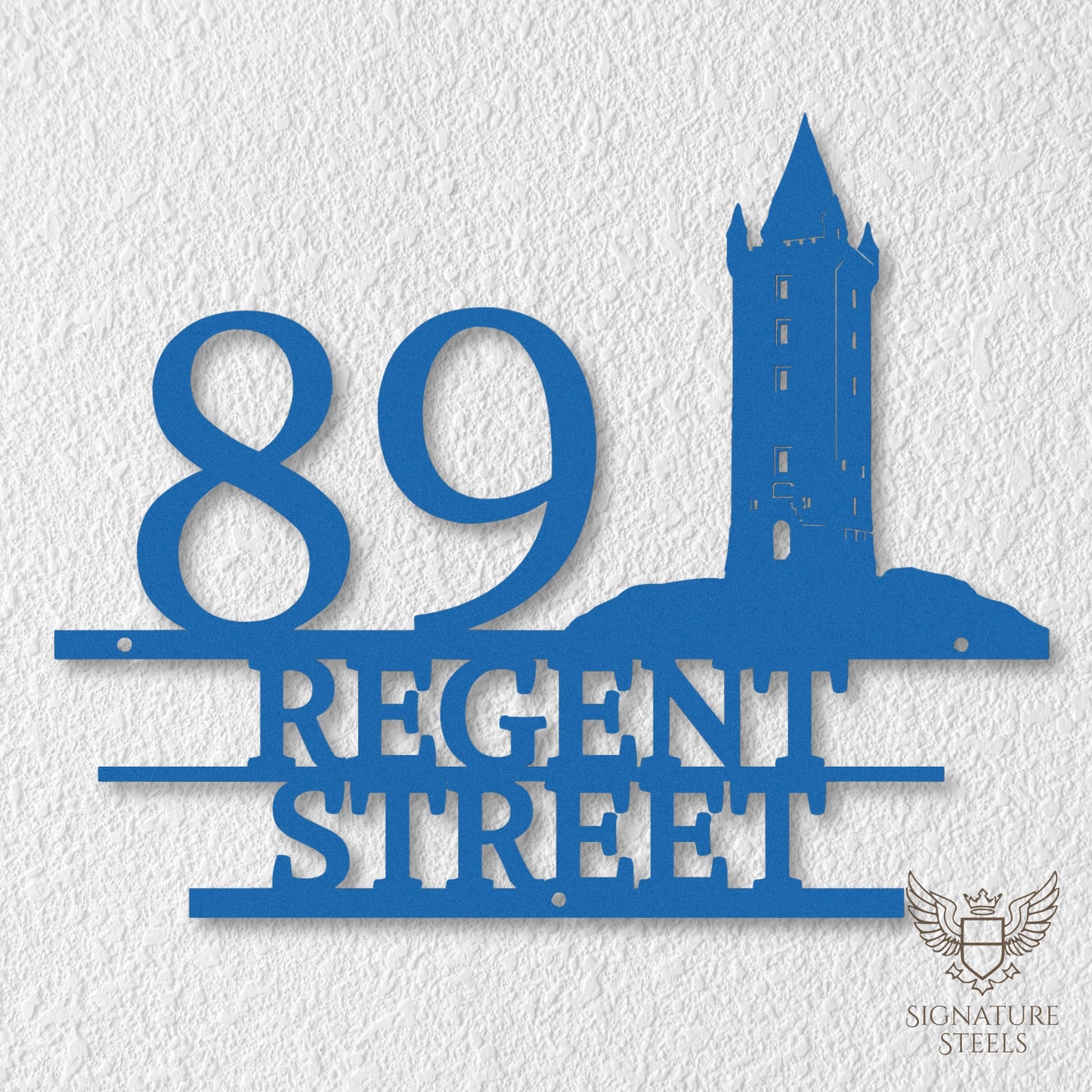 Blue metal address sign with house number 89, street name Regent Street, horizontal parallel lines and a silhouette of Scrabo Tower, a landmark of Newtownards in Northern Ireland, hanging on a white exterior wall.