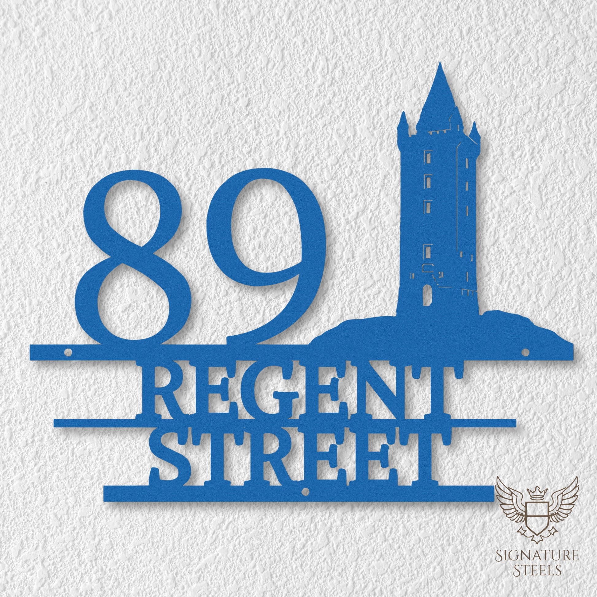 Blue metal address sign with house number 89, street name Regent Street, horizontal parallel lines and a silhouette of Scrabo Tower, a landmark of Newtownards in Northern Ireland, hanging on a white exterior wall.